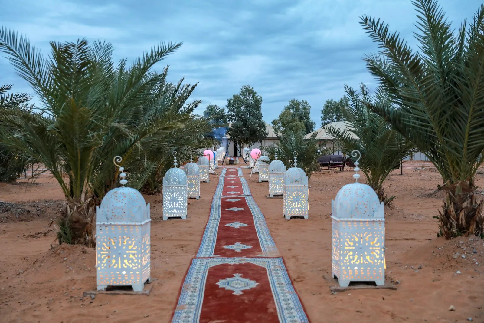 Allée de cérémonie dans le désert, lanternes marocaines et tapis au crépuscule